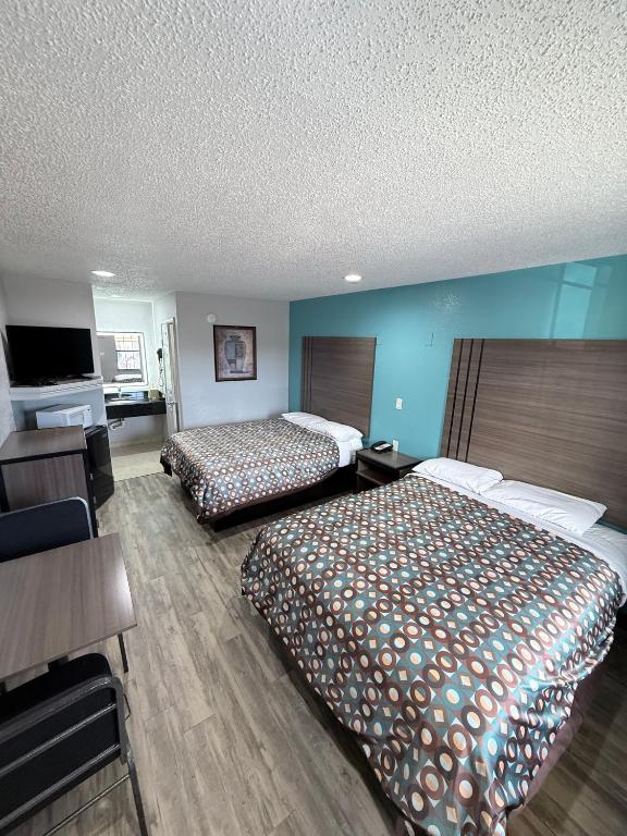 a hotel room with two beds and a flat screen tv at Relax Inn Bryan College Station in Bryan