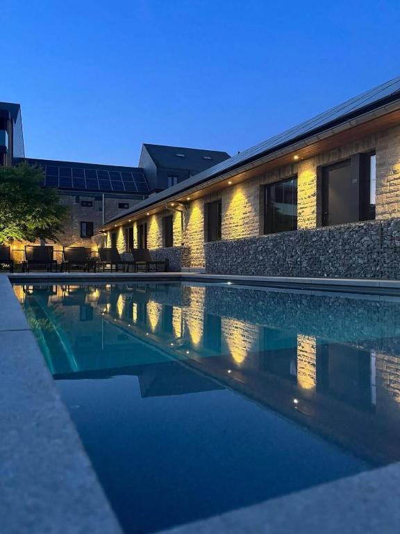 a swimming pool in front of a building at night at B&B Au Cœur de Han in Han-sur-Lesse