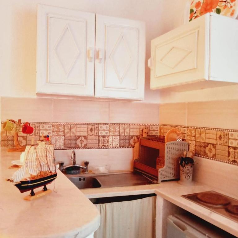 a kitchen with white cabinets and a microwave at Bungalow kantaoui Sousse in Hammam Sousse