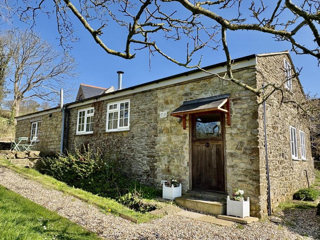 an old stone house with a wooden door at Blackmoor View Cottage in Sherborne