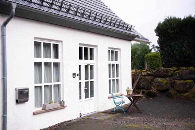 a white house with a blue chair and a table at Alte Schreinerei in Steffeln
