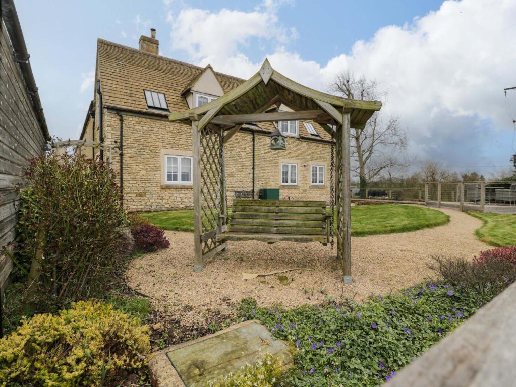 a wooden bench in front of a house at Stanbridge Cottage in Malmesbury