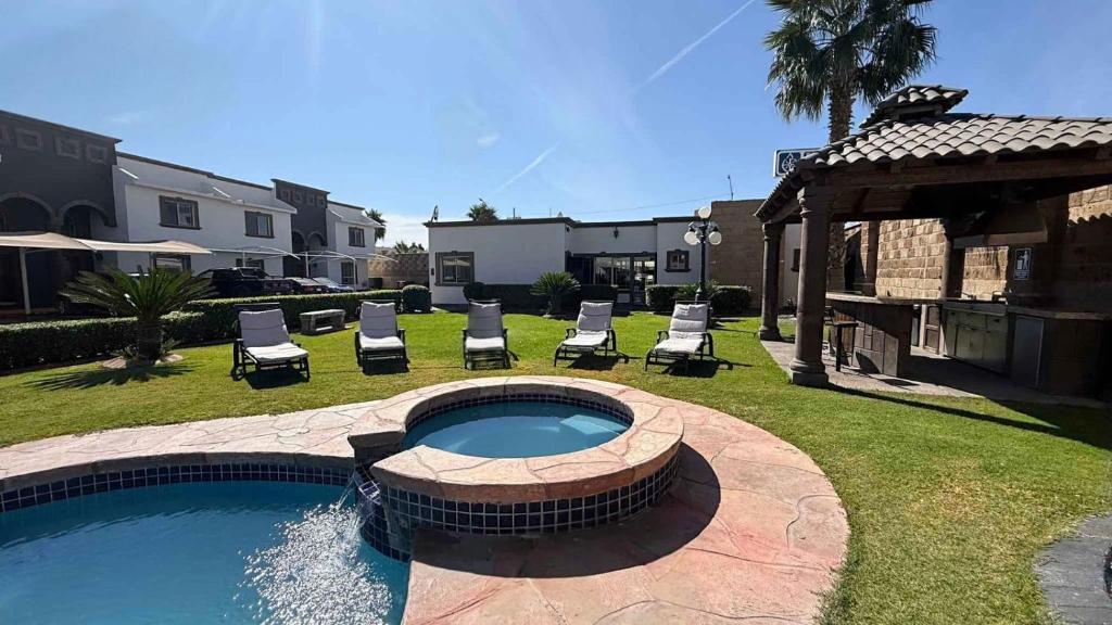 a backyard with a swimming pool and chairs and a house at Arroyos del Paraíso Residencial Suite B in Manuel F. Martínez