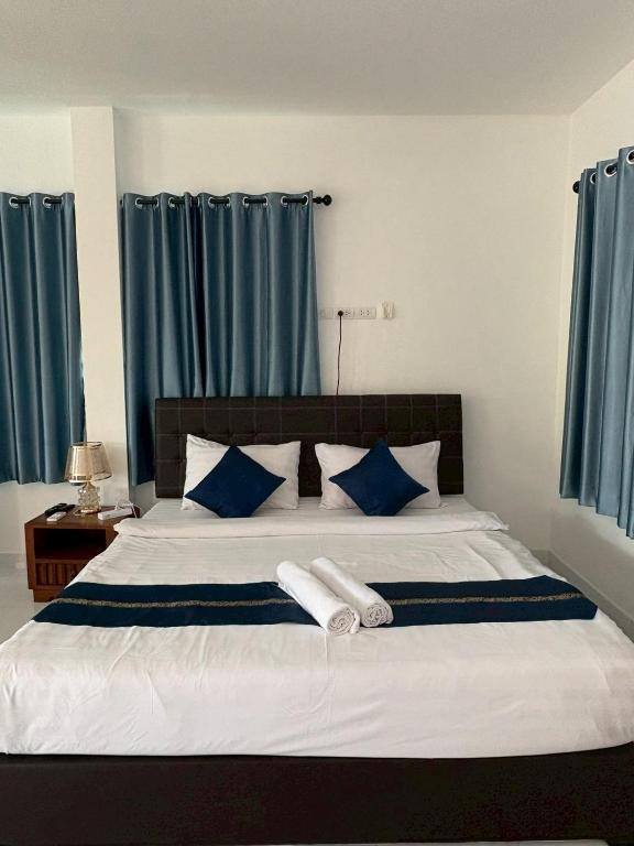 a bedroom with a large bed with blue curtains at AN Airport Guesthouse in Nai Yang Beach