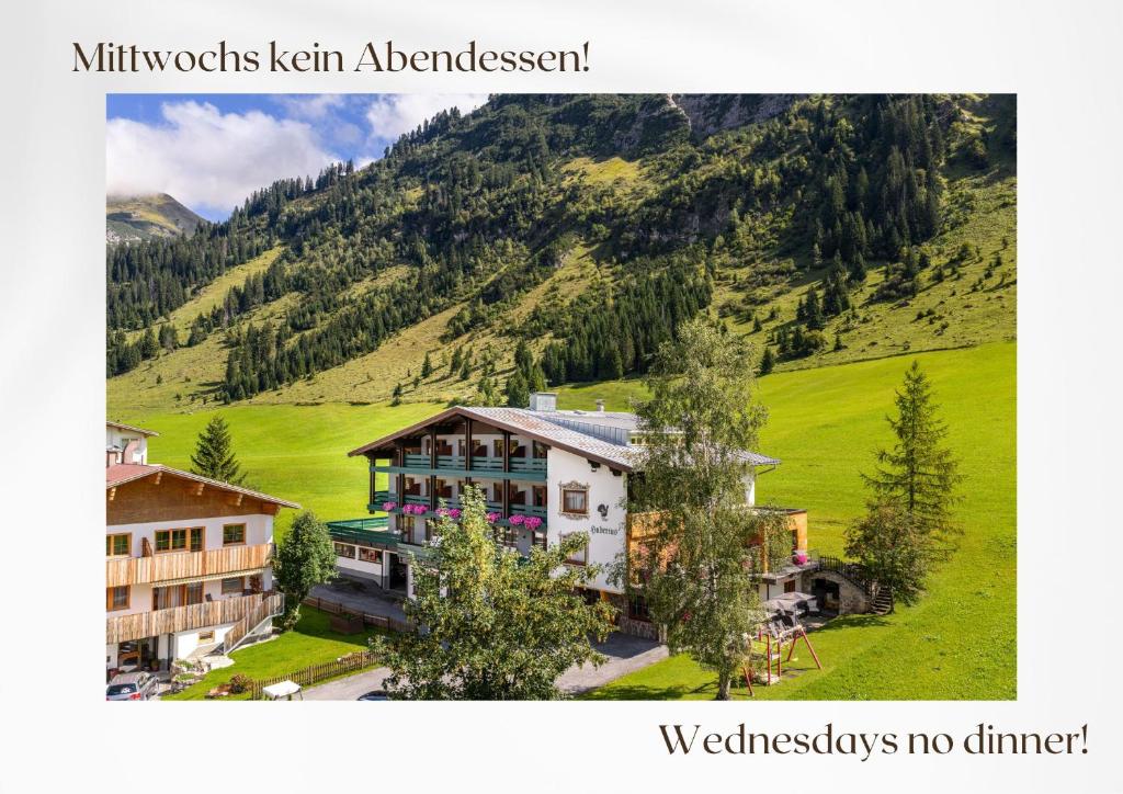 a building in a field with a mountain in the background at Hubertus, 3 Sterne Superior in Lech am Arlberg