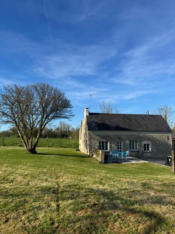 an old stone barn in a field with a tree at Gîte à Travers champs in Colombières