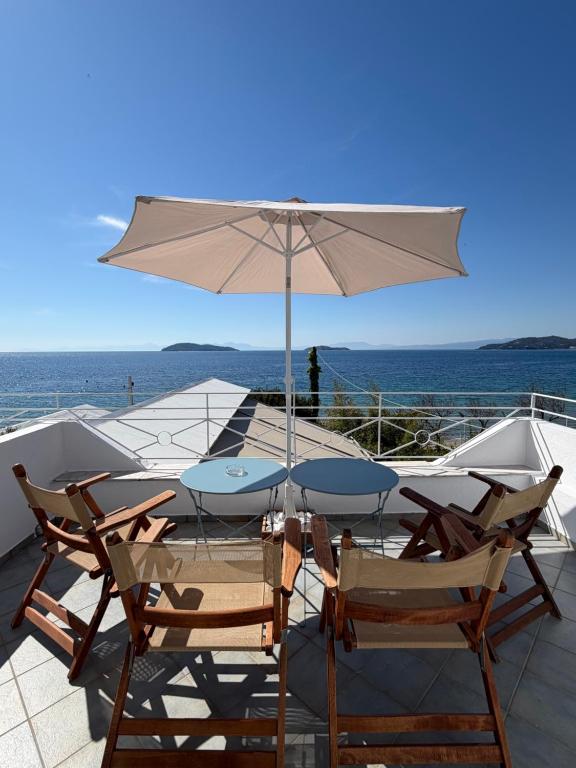 a table and chairs with an umbrella on a balcony at Lenio Rooms in Skiathos
