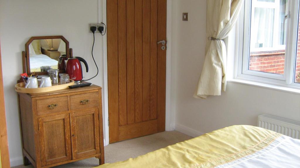 1 dormitorio con cama, espejo y puerta de madera en Savannah Bed and Breakfast, en Virginia Water