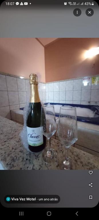 a bottle of wine and two glasses on a counter at Motel Viva Vez in Canoas