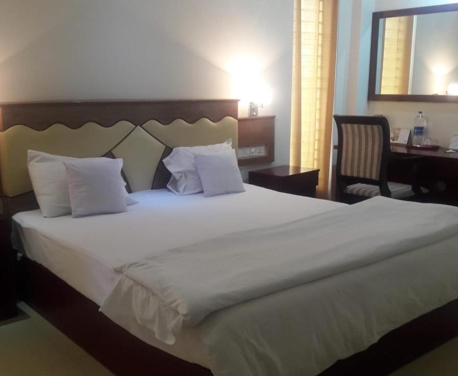 a bedroom with a large white bed and a desk at Hotel Crown in Rājshāhi