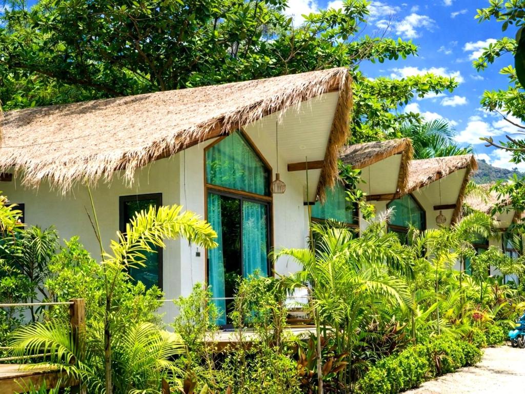 a house with a thatched roof in a garden at Crystal Bungalow DELUXE in Ko Phangan