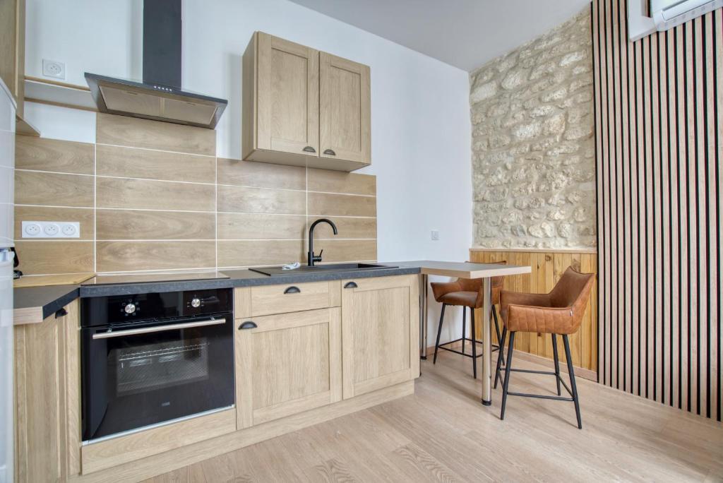 a kitchen with wooden cabinets and a sink and a table at Studio 2p rénové - Centre 5min- Stationnement in Angoulême