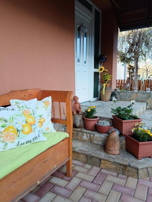 a wooden bench sitting on a patio with potted plants at Hársfa apartman in Makó