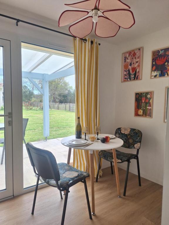 a dining room with a table and chairs and a window at La Pinède du Chéou, Piscine, Logement indépendant, Parking, Draps, Wifi fibre in Mimizan