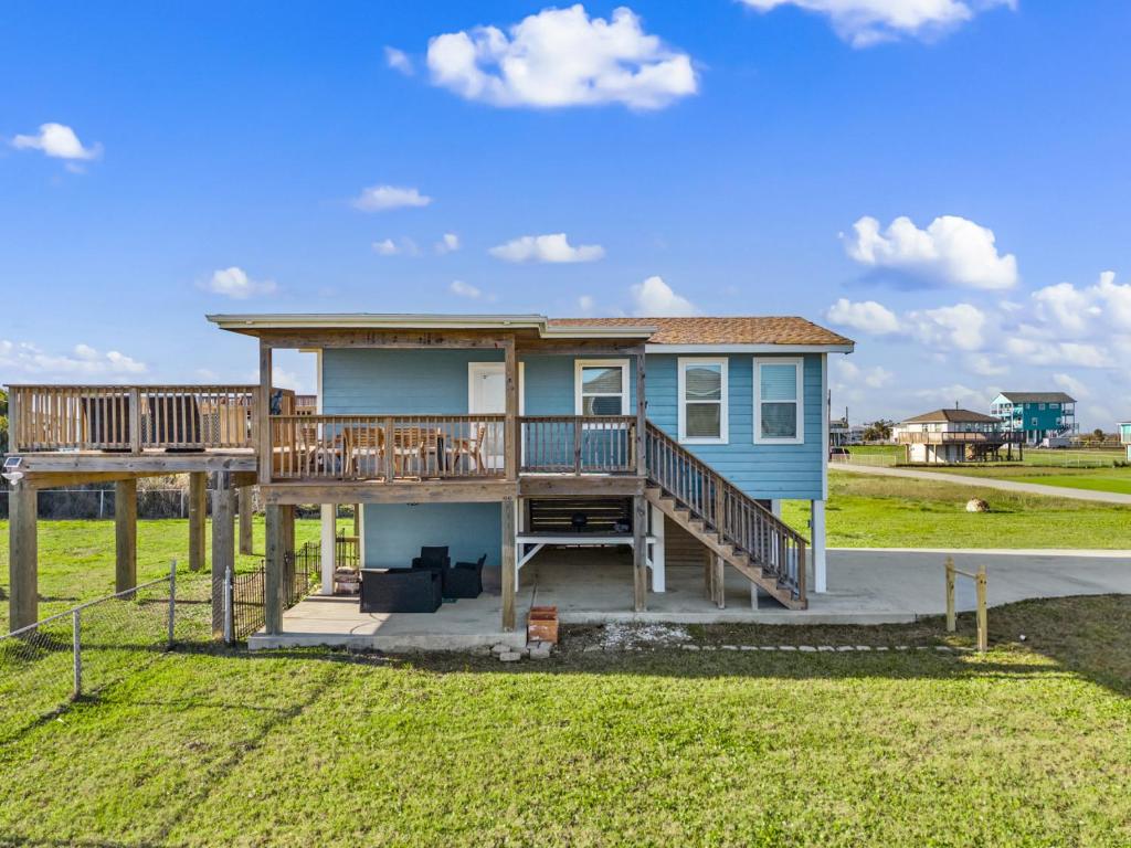 a blue house with a large deck and grass at Chulavista Cozy Close to beach in Galveston
