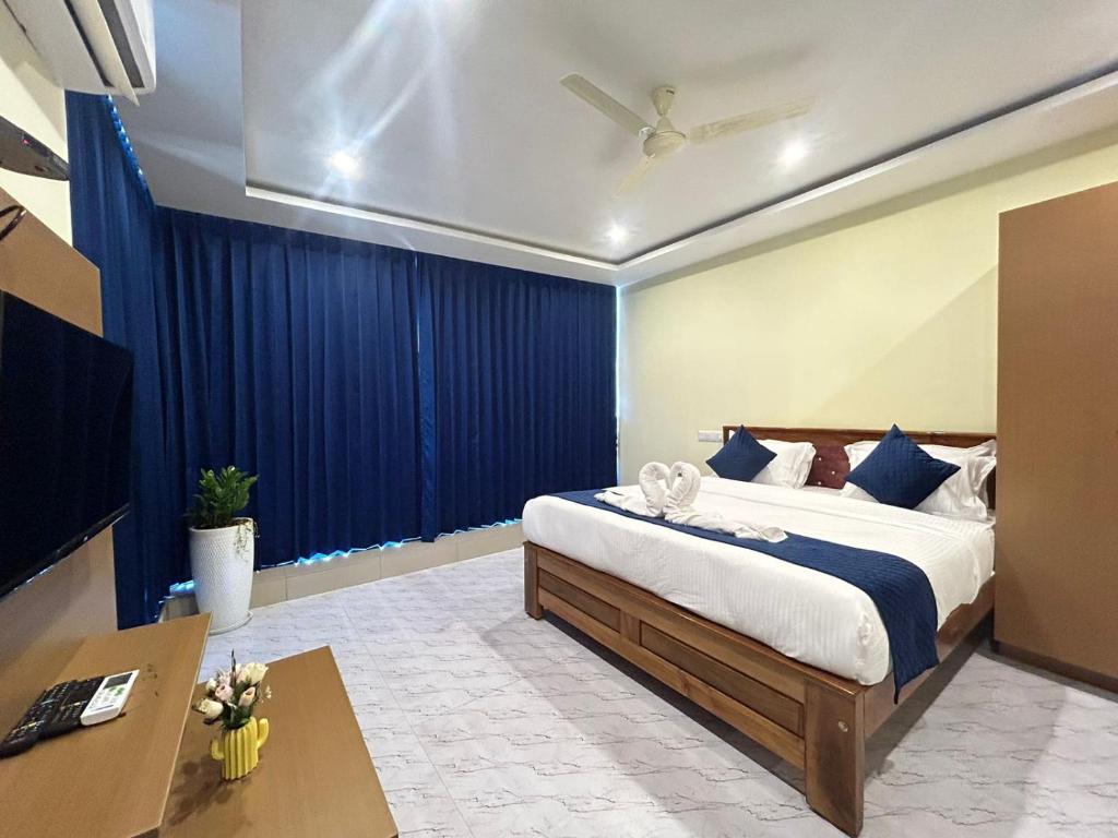 a bedroom with a large bed with blue curtains at SB Royal Inn in Mysore