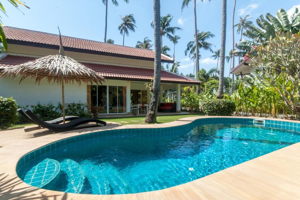 a swimming pool in front of a house at Malee Beach F3 in Phra Ae beach