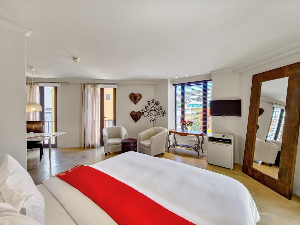 a bedroom with a large white bed and a living room at Rouge on Rose Boutique Hotel in Cape Town
