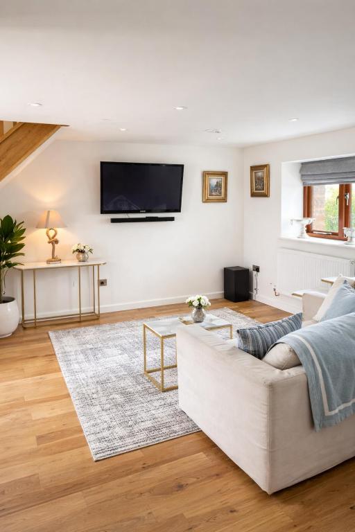 a living room with a white couch and a tv on the wall at Careful Cottage in Crediton