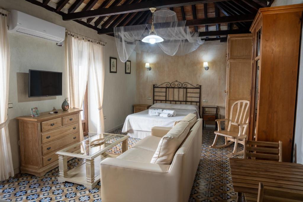 a bedroom with a bed and a couch and a table at Casa de las Remigias in Estepona
