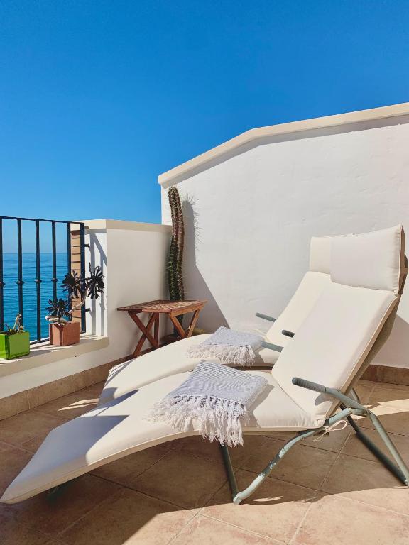 a white chair on a balcony with a view of the ocean at Ático dúplex - 1ª Linea playa in Adra