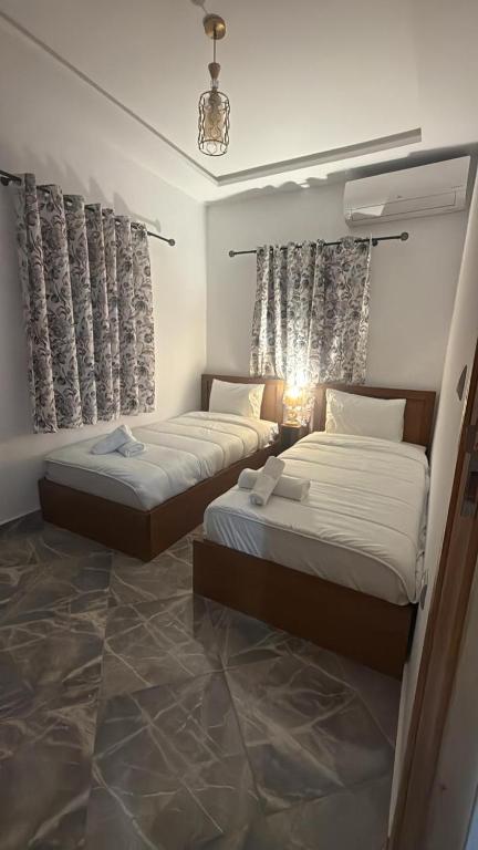two beds in a hotel room with curtains at Casa Si Ahmed in Chefchaouen