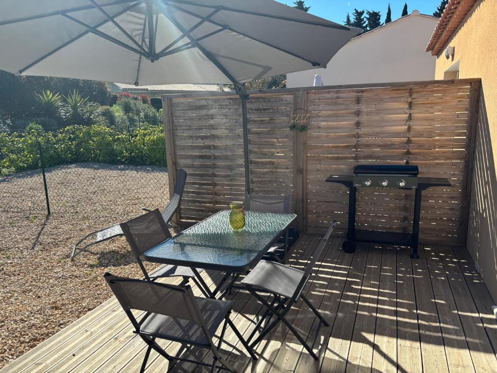 a table and chairs with an umbrella on a deck at la pause detente, villa climatisée avec jardin et parking privés, à 5 mn de la mer, au calme in Martigues