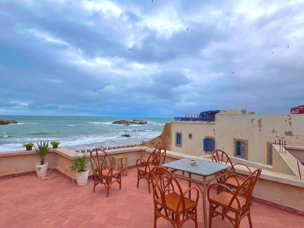 a patio with a table and chairs and the ocean at Riad Sor in Essaouira