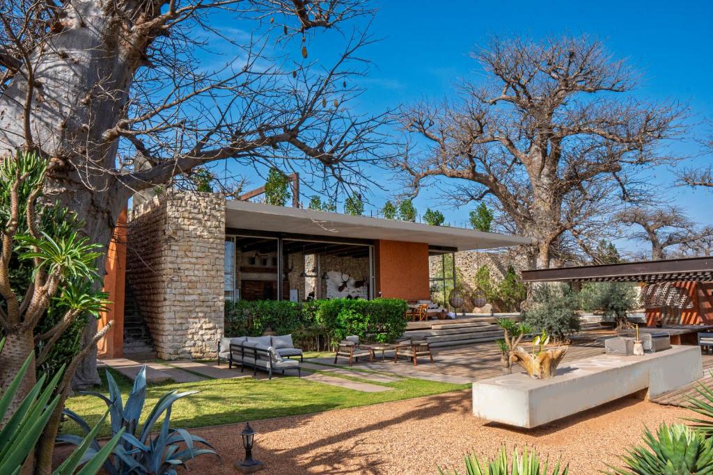a brick house with a patio and trees at Casa del Toro Luxury Ranch in Nguékokh