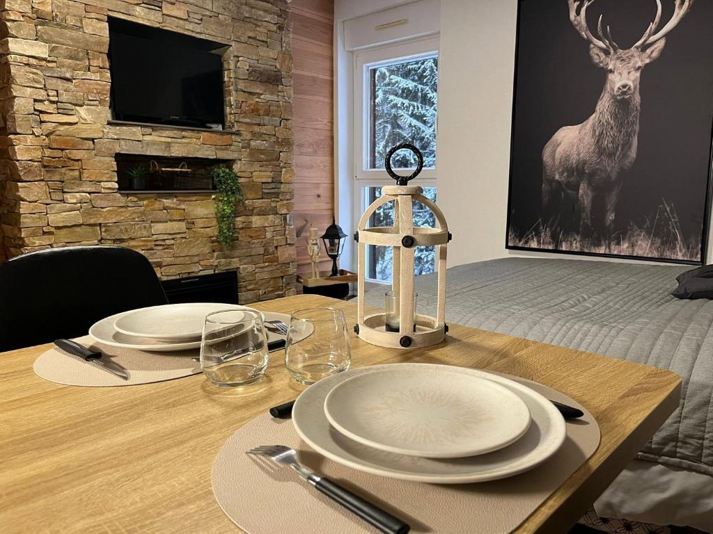 a wooden table with plates and glasses on top of it at Studio Chalet des Pistes in Gérardmer