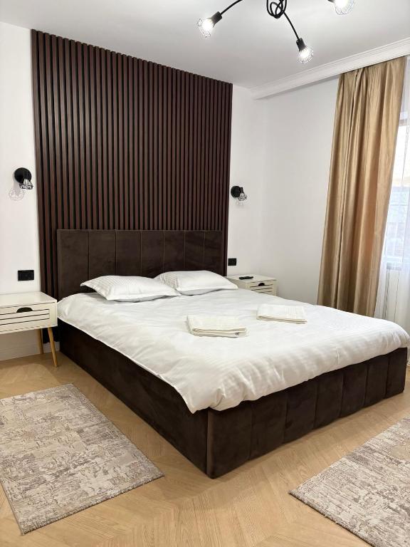 a bedroom with a large bed with a wooden headboard at Borșa ApartHotel 5 in Borşa