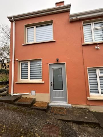 a pink house with a gray door on a street at Colony Retreat in Dingle