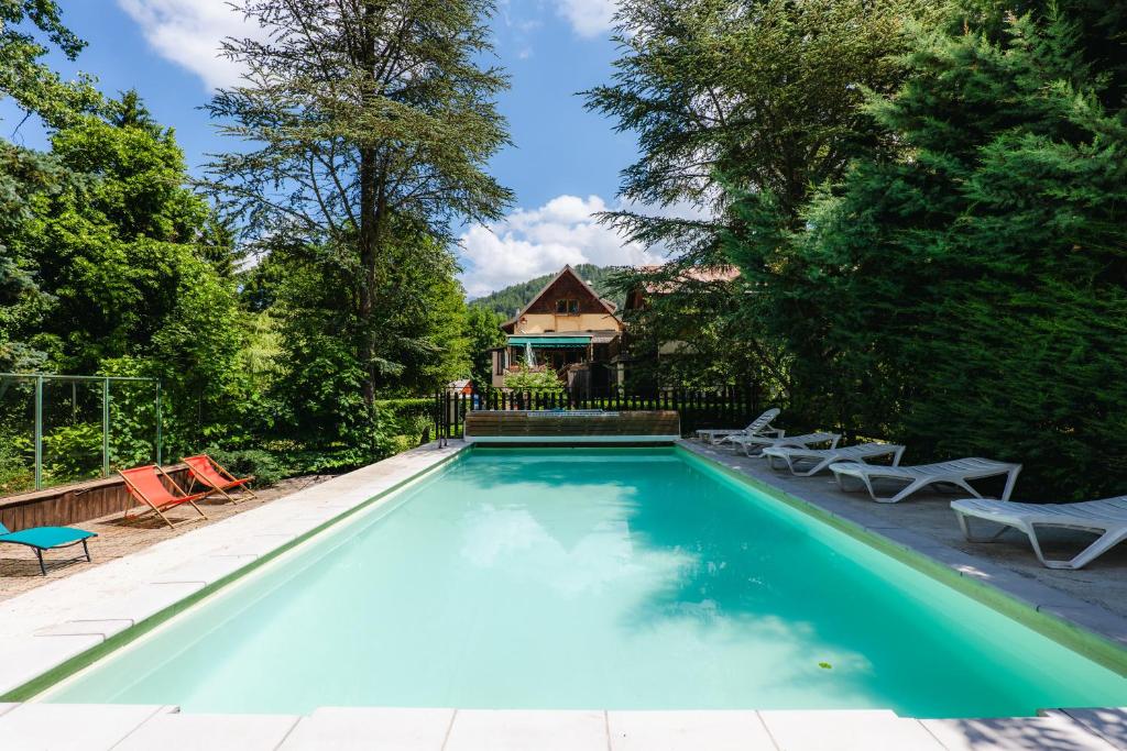 a swimming pool with chairs and a house at Le Vieux Tilleul in Seyne