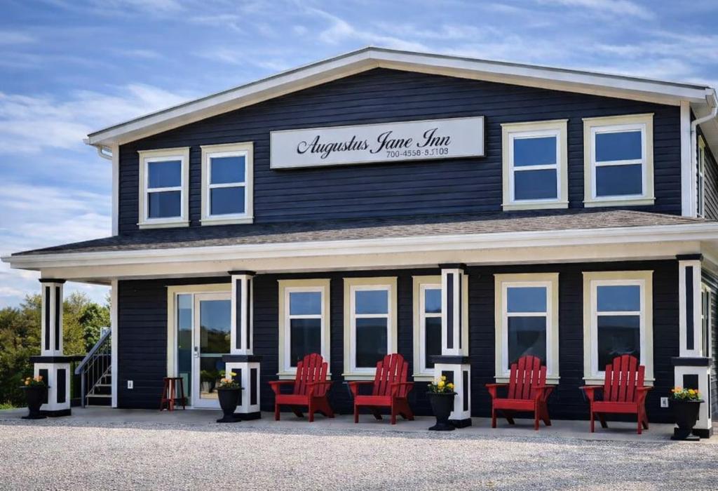 a group of red chairs in front of a black building at Augustus Jane Inn in Rocky Harbour