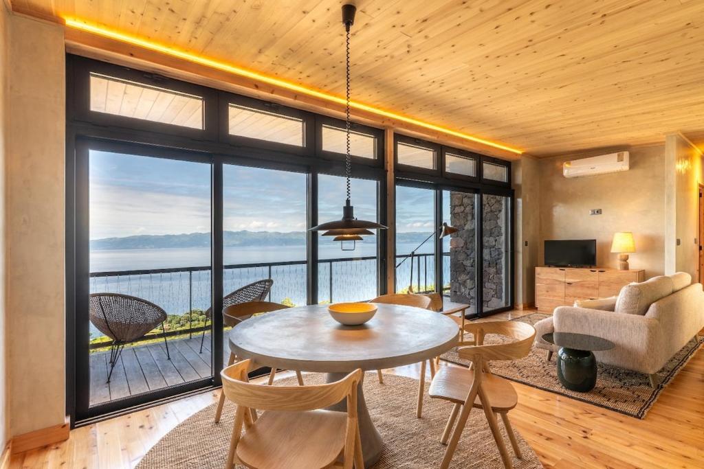 a living room with a table and chairs and a large window at Casa Aromas in Santo Amaro