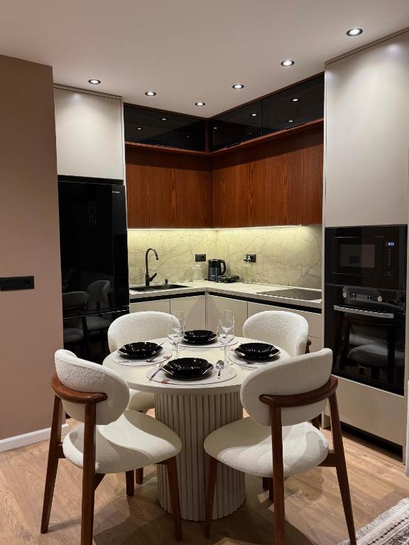 a kitchen with a table with white chairs and a kitchen at FIN Skyline Apartment in Krujë