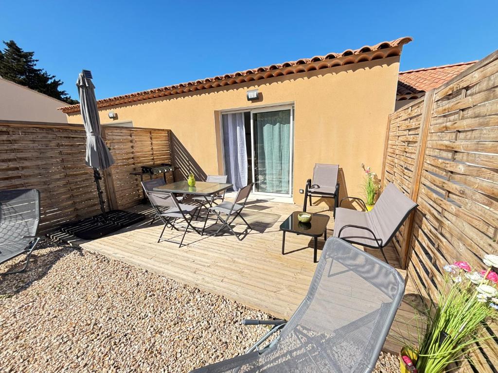 a wooden deck with chairs and an umbrella at la pause soleil, villa climatisée, avec jardin et parkings privés, à 5 mn de la mer, au calme in Martigues