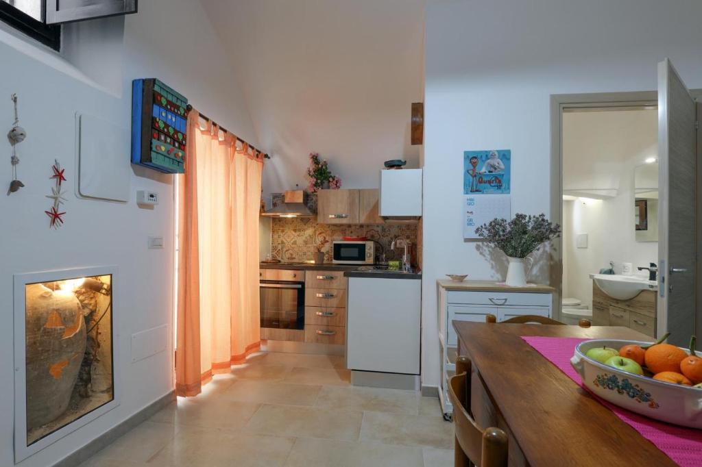a kitchen with a table with a bowl of fruit on it at Le Pozzelle Presicce, Bilocale Casa a Corte XVI sec in Presicce