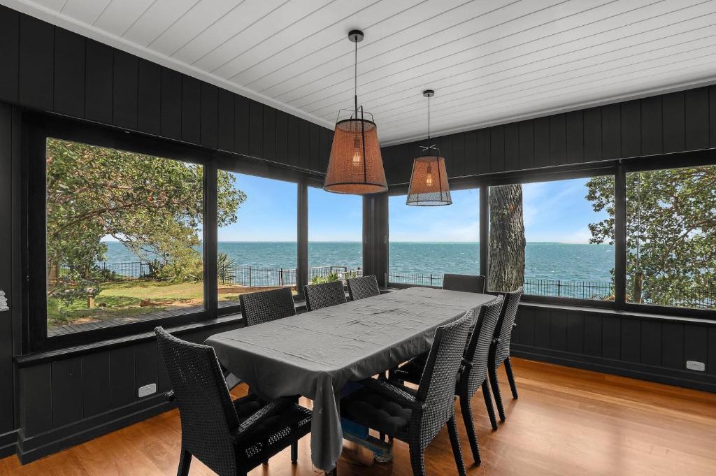 a dining room with a table and chairs and the ocean at Dolphins at Sunset in Amity Point