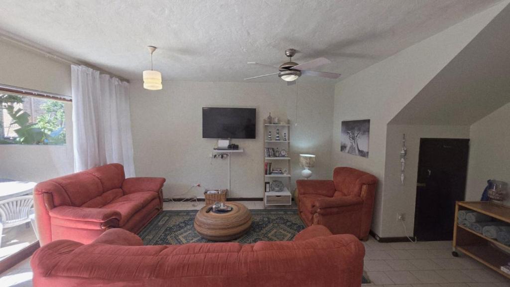a living room with two red couches and a tv at Beach Bliss Retreat in Margate