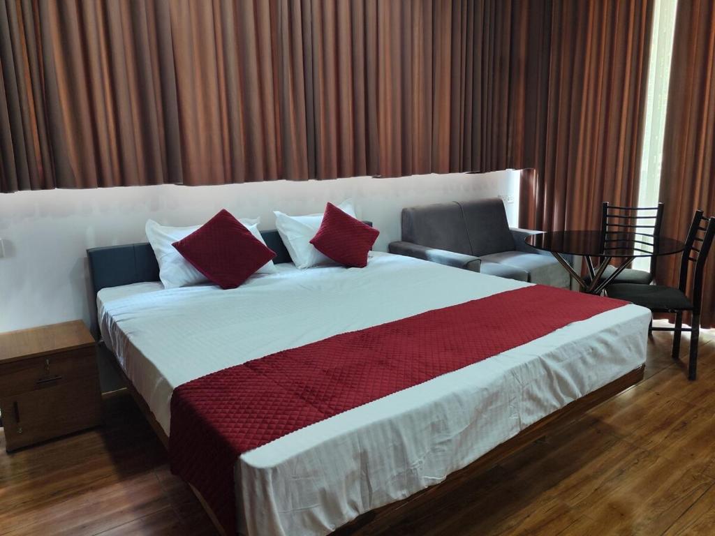 a bedroom with a large white bed with red pillows at Spice Garden Clove Villa in Batheri