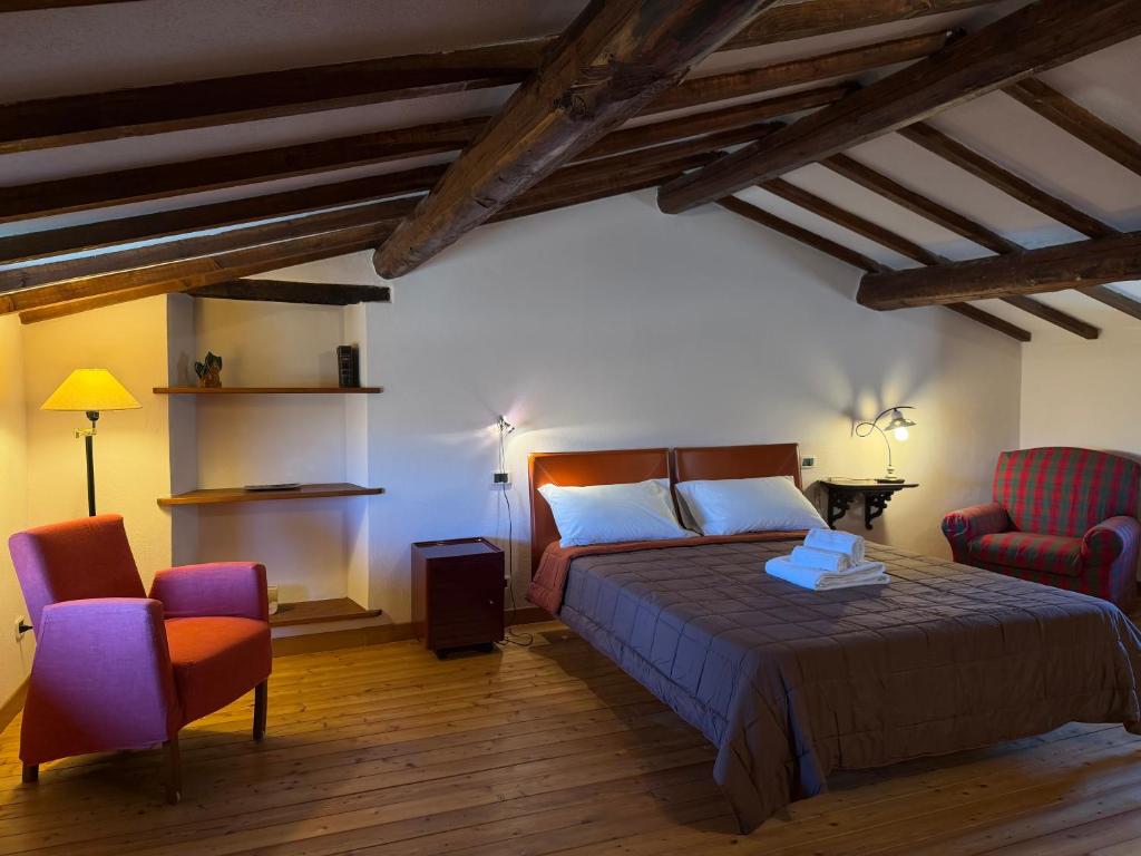 a bedroom with a bed and two chairs at Campanile N1 in Montemerano