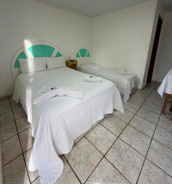 a bedroom with a large bed with white sheets at Hotel empresarial HARRY WORLD in Curitibanos