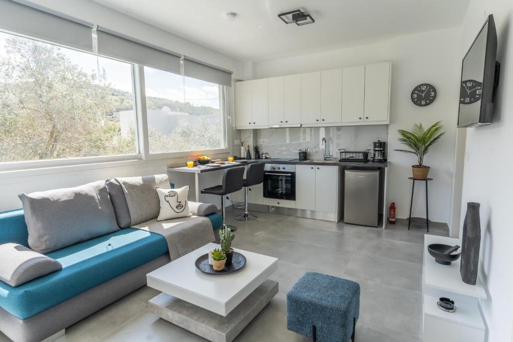 a living room with a blue couch and a kitchen at Basil Leaf - Minimal View Retreat in Gonia
