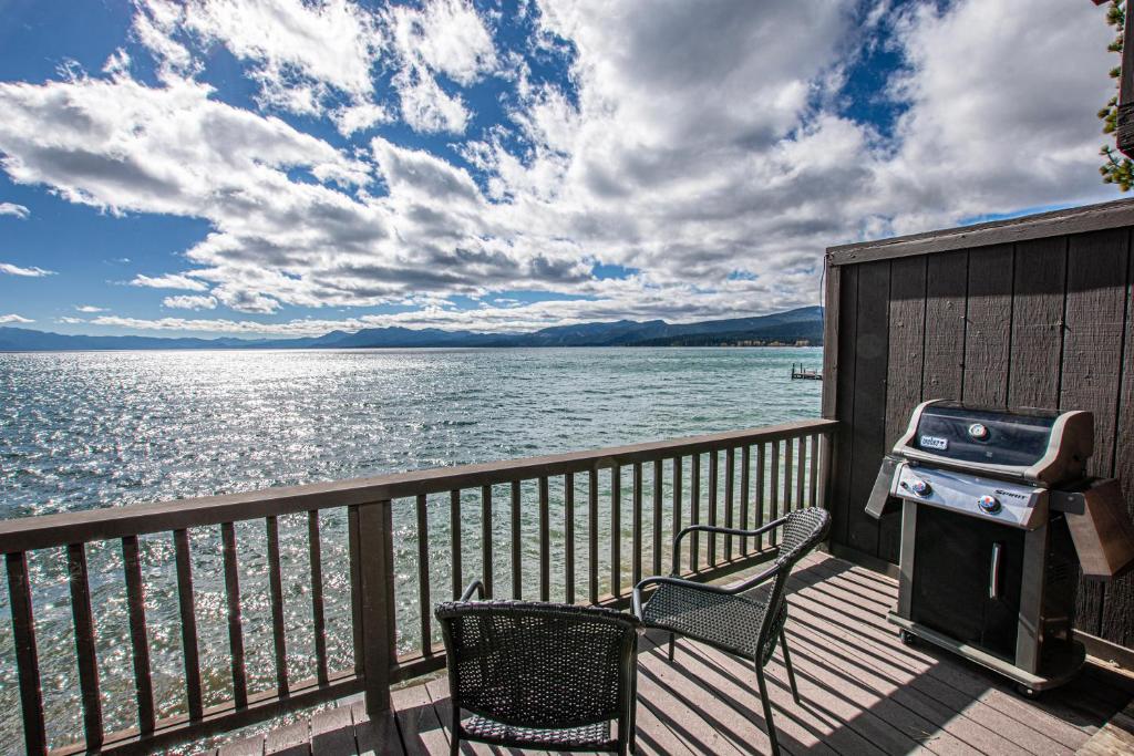 a grill and a chair on a deck next to the water at Star Harbor # 13 By Hauserman Rentals in Tahoe City