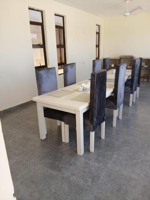 a dining room with a white table and chairs at Kimbar Suites in Mombasa