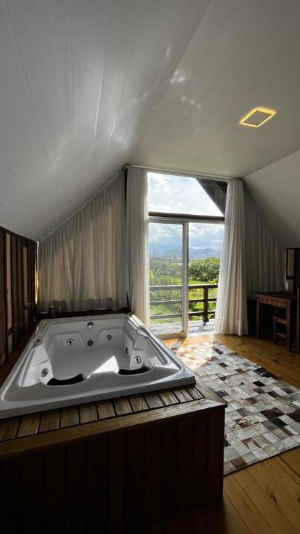 a bath tub in a room with a large window at cabana refúgio in Paulo Lopes