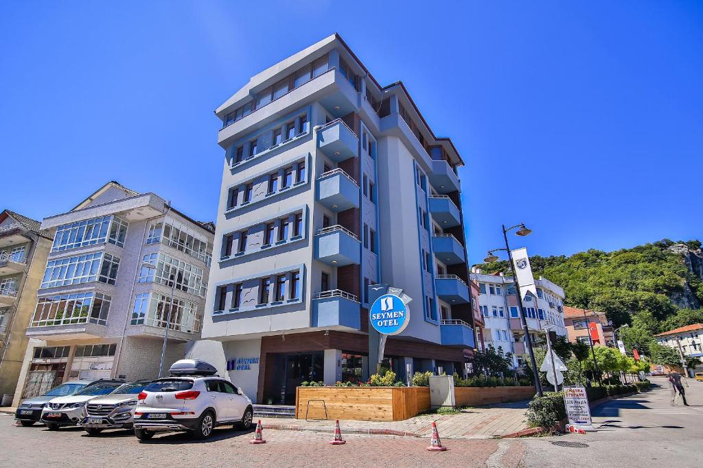 a tall building with cars parked in a parking lot at Seymen Hotel in Amasra