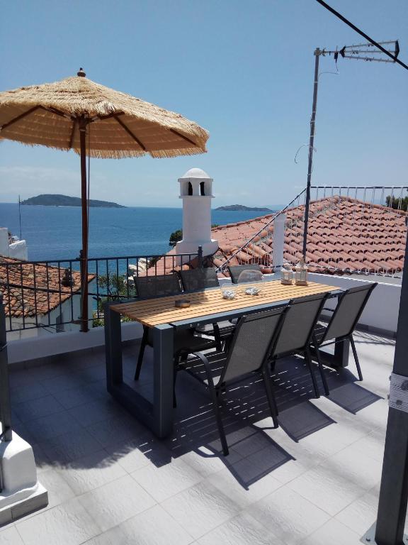 a wooden table with chairs and an umbrella on a balcony at Reborn Project Plakes in Skiathos