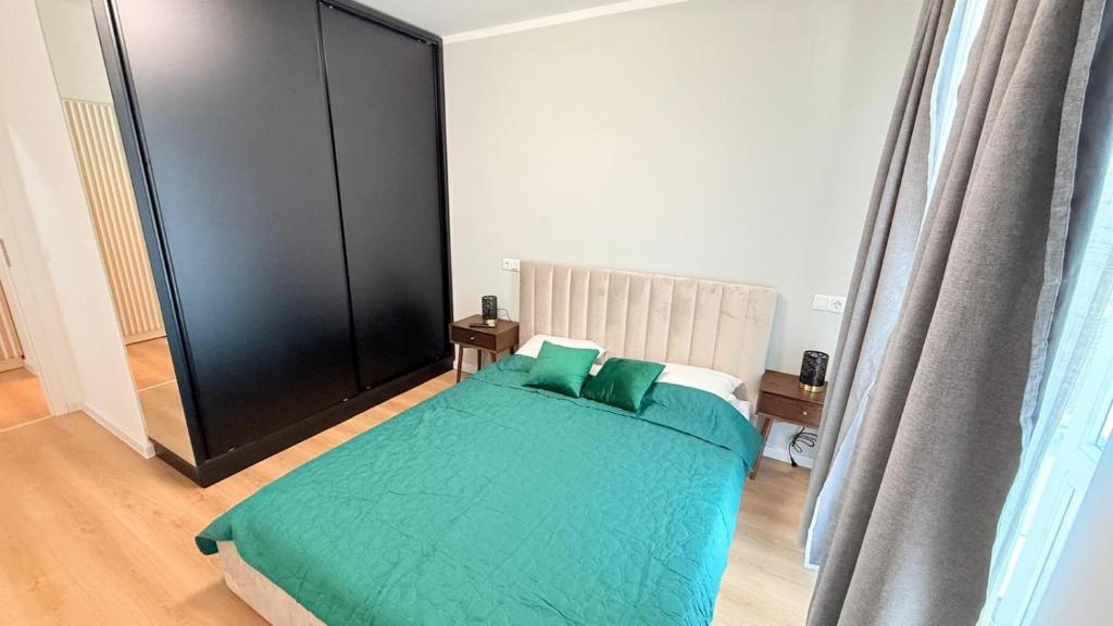 a bedroom with a bed with green sheets and pillows at TRIO Sun Class Park Residence in Târgovişte